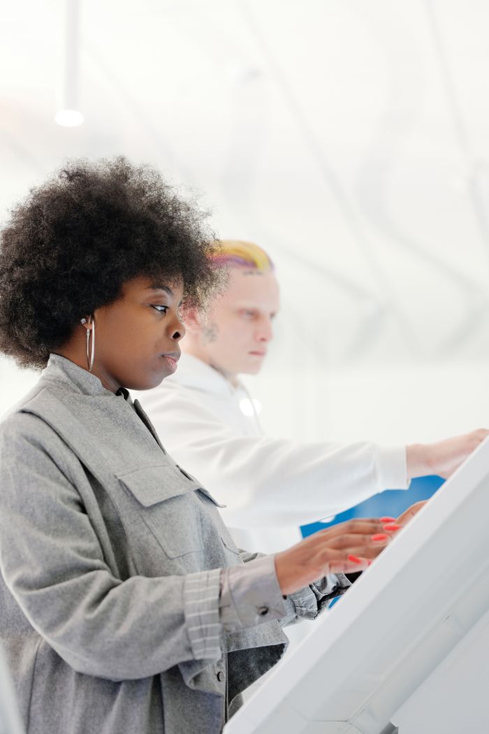gallery-1 Side view of a stylish woman with afro hair using a touchscreen indoors.